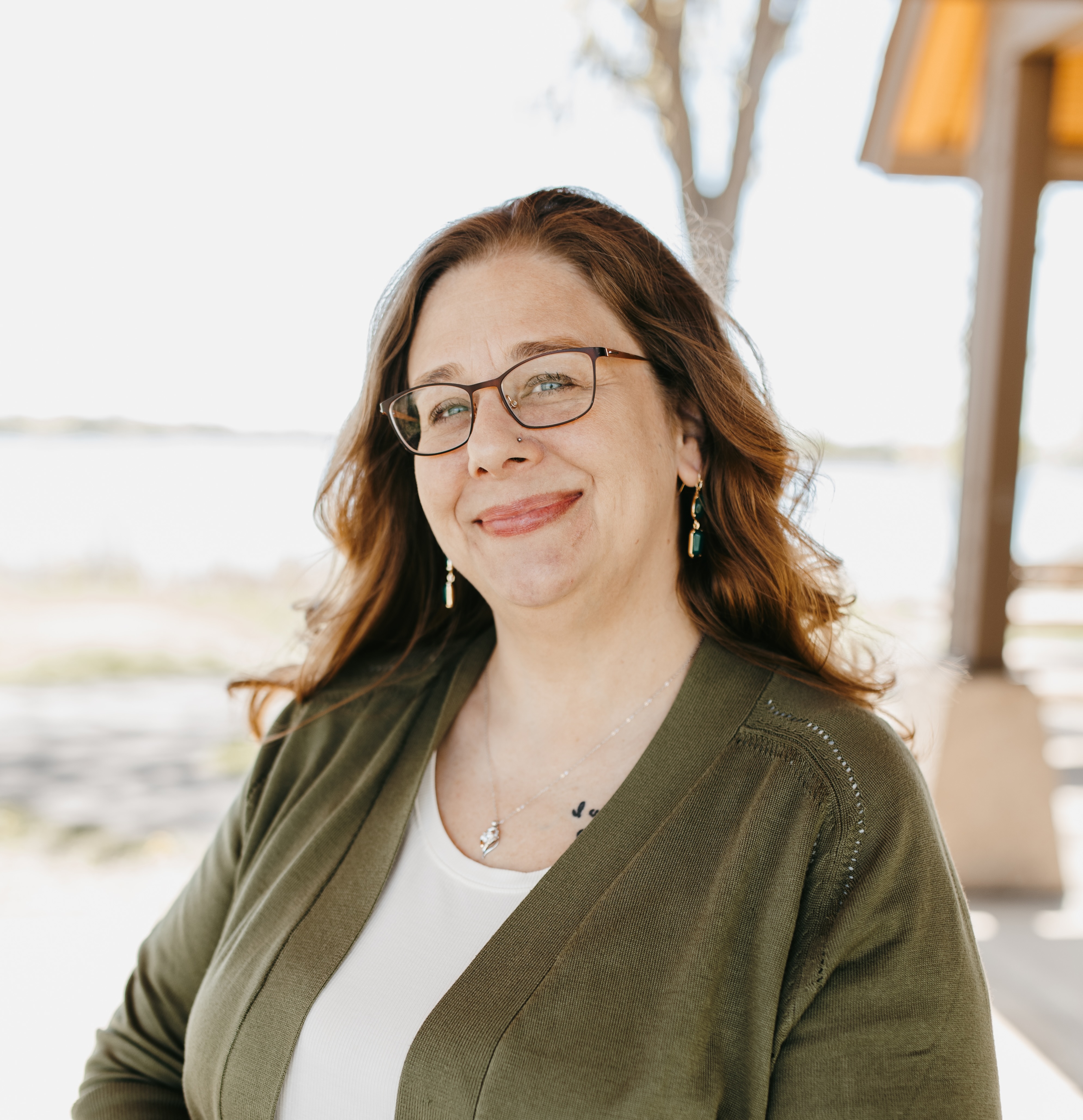 woman with dark hair and green sweater sitting outside on picnic table