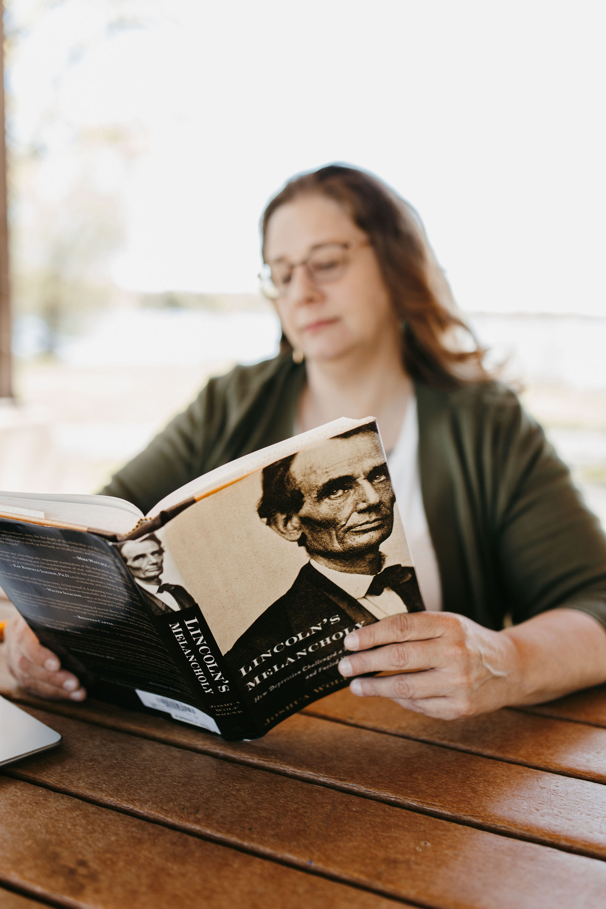 woman in green sweater reading abraham lincoln textbook