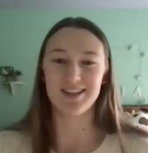woman with long dark hair with green wall behind