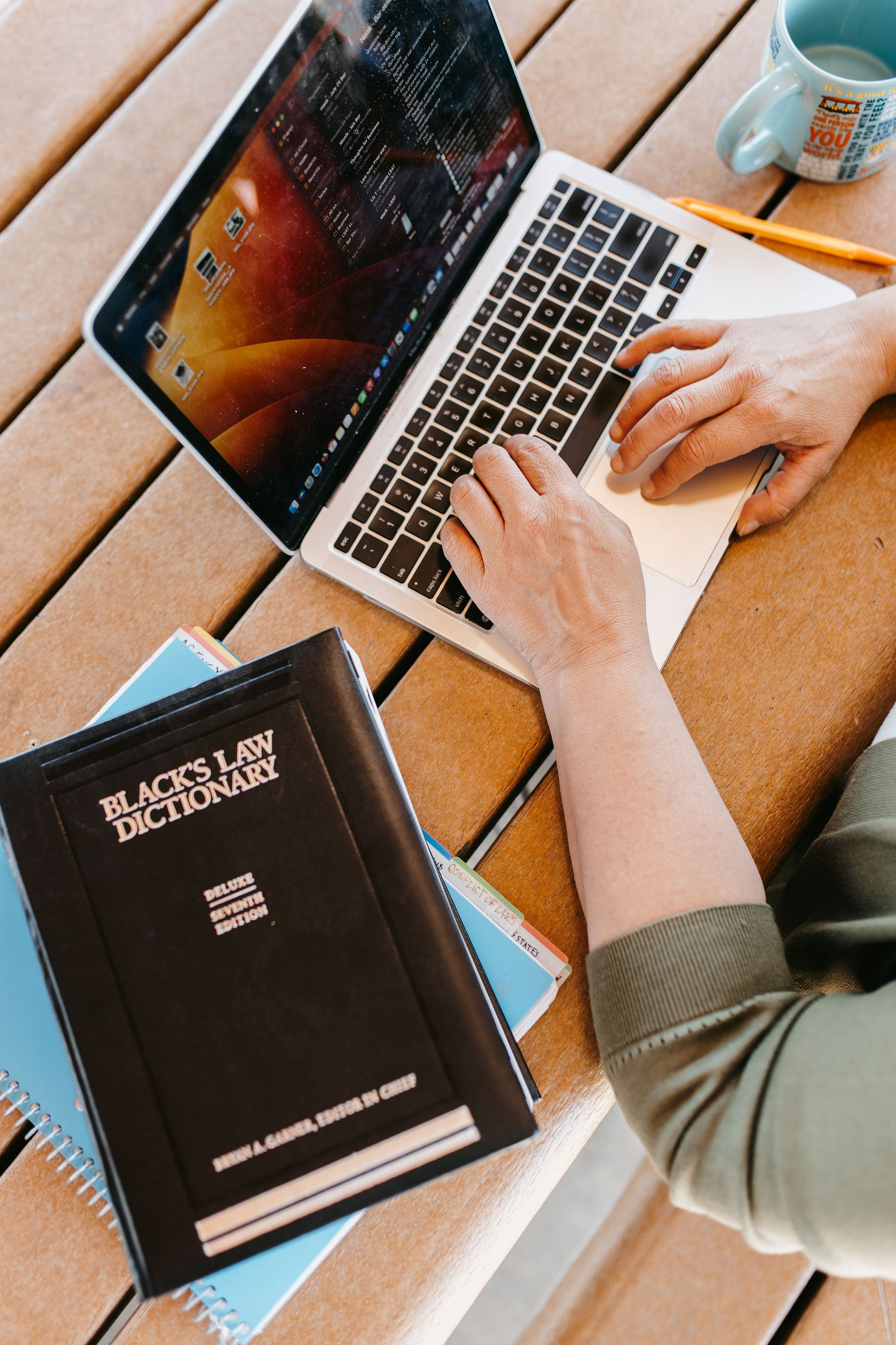 woman working on laptop on picnic table with black laws dictionary