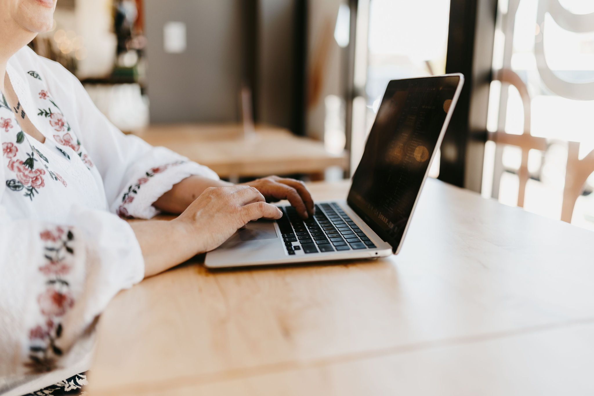 woman working on laptop with white floral blouse